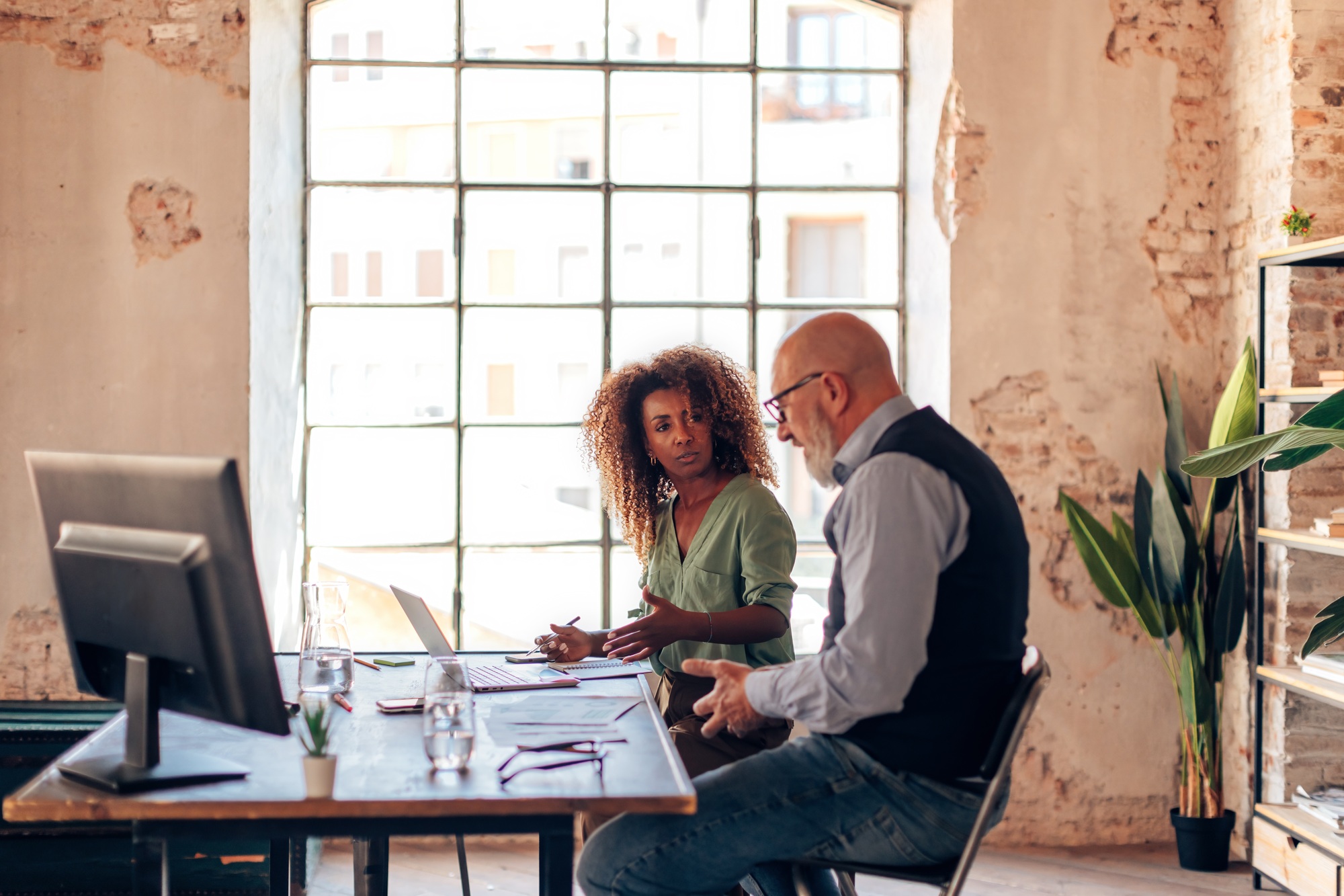 multiethnic colleagues sitting at desk in cozy bureau working together on enterprise planning multiethnic colleagues sitting at desk in cozy bureau working together on enterprise planning